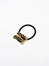 Colero elástico negro con pieza decorativa metálica dorada de diseño abombado y estampado animal print en negro.