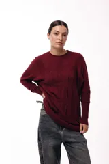 Sweater de punto con textura en color bordó, de silueta relajada, cuello redondo y mangas largas con puños ajustados.