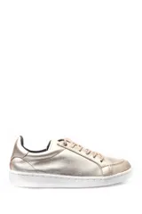 Zapatilla deportiva de cuero metalizado en tono dorado, con suela plana de goma blanca y cierre mediante cordones al tono.