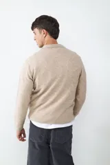 Sweater de punto con cuello polo y cierre frontal de botones. Presenta puños y ruedo acanalados, con un diseño de textura suave y abrigada.