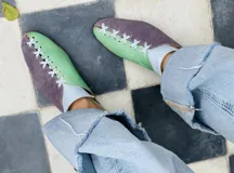 Zapatos tipo mules de punta cerrada y talón abierto, con diseño bicolor que combina cuero metalizado dorado y tono mostaza. Presentan detalles de costuras cruzadas en contraste sobre el empeine y suela baja.
