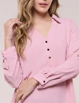 Blusa verde de calce holgado y caída fluida, confeccionada en tejido tipo crepé. Cuenta con cuello camisero con solapa, escote en V y cierre parcial al frente con tres botones metálicos. Las mangas son largas con puños abotonados.