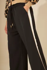 Pantalón negro de corte palazzo con cintura elástica y raya lateral blanca.