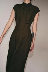 Vestido midi de Zara Woman Collection, confeccionado en mezcla de viscosa y lyocell. Presenta cuello perkins con lazada frontal, diseño sin mangas, pliegues en la cintura y cierre posterior con abertura y botones.