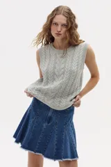 Chaleco de punto color gris melange, con cuello redondo, sisa amplia y largo a la cadera. Presenta un diseño de ochos tradicionales.