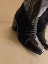 Botas estilo texanas de caña media, color negro, combinadas en cuero y gamuza, con punta cuadrada y taco medio.