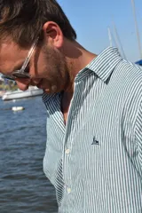 Camisa de manga larga con estampado de rayas verticales en color verde y blanco. Presenta cuello clásico, cierre frontal con botones y logo bordado en el pecho.