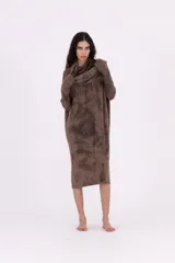 Vestido de tejido de punto gris oscuro con efecto tie-dye o marmolado, silueta amplia y largo midi. Posee cuello tortuga caído y mangas largas con abertura para el pulgar.