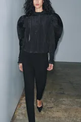 Blusa negra de cuello alto y manga larga abullonada con puños abotonados. Tejido arrugado y cierre frontal oculto con botones. Zara Woman Collection.