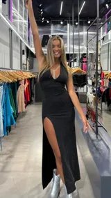 Vestido largo negro de lurex con brillos, escote halter en V, espalda descubierta y una abertura lateral alta en la falda.