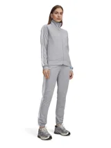 Conjunto deportivo Under Armour de tricot gris, compuesto por una campera con cierre frontal y cuello alto, y un pantalón de jogging con cordón ajustable en la cintura y franjas blancas laterales.