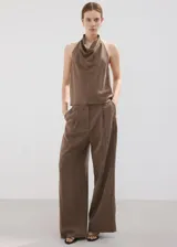Pantalón de corte recto y tiro regular, color marrón, con bolsillos laterales y traseros con ribete. Cierre frontal con cremallera, botón y ganchos ocultos.