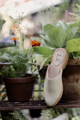 Mules de cuero negro con tachas plateadas en el borde de la suela y plantilla con logo estampado.