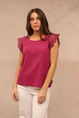 Blusa fucsia sin mangas con cuello redondo y detalles de encaje broderie en los hombros.
