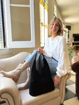 Bolso tipo tote bag negro de cuero, con costuras a la vista y manijas cortas.