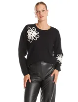 Buzo tejido color negro con cuello a la base y mangas largas. Presenta un diseño floral en relieve en color blanco ubicado en la parte superior delantera y en la parte inferior de una de las mangas.