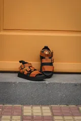 Sandalias de cuero color terracota con plataforma negra y hebillas negras.