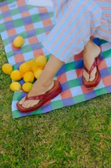 Sandalias estilo chancla de plataforma corrida, color rojo con acabado brillante y tiras anchas en forma de V.