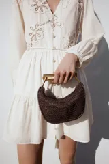 Mini bolso marrón trenzado con asa de mano dorada metálica y doble asa bandolera ajustable y extraíble. Incluye forro, bolsillo interior y cierre mediante cremallera.
