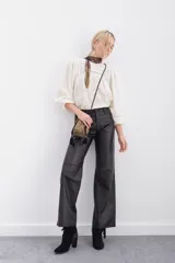 Pantalón de cuero ovino con corte oxford y tiro medio. Presenta diseño de cinco bolsillos, cierre frontal con botón metálico y costuras horizontales a la altura de la rodilla.