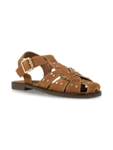 Sandalia plana tipo guillermina y cangrejera, confeccionada en cuero gamuza color camel, con tiras cruzadas decoradas con tachas metálicas doradas. Cuenta con tira ajustable en el talón con hebilla metálica y suela de caucho.
