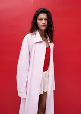 Chaqueta larga de algodón color rosado, de diseño recto con cuello solapa, manga larga, bolsillos laterales y cinturón tipo batín.