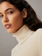 Sweater ajustado de punto de canalé color crema, con cuello alto y logo bordado en el ruedo.