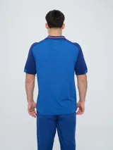 Remera polo deportiva Umbro del Club Nacional de Football, color azul con cuello en V y detalles en rojo y blanco. Incluye el logo de Umbro y el escudo del club.