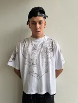 Remera de algodón pesado con corte boxy fit, color blanco con efecto acid wash. Presenta un estampado frontal y en mangas que simula una armadura medieval con acabado gastado.