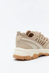 Zapatilla deportiva de estilo trekking con diseño técnico y urbano. Presenta una estructura combinada de paneles de malla y piezas de poliuretano, con sistema de cordones integrado y suela robusta con relieve para mayor estabilidad.