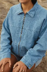 Campera de jean celeste de corte oversize con cierre frontal de cremallera metálica y cuello camisero. Posee bolsillos laterales y puños abotonados.