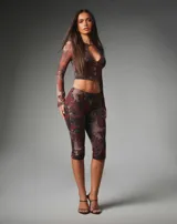 Conjunto de dos piezas de mesh elastizado con estampado floral y animal print, compuesto por un top corto de manga larga con cierre frontal de botones y abertura tipo lágrima, y un pantalón capri de tiro medio y calce ajustado.