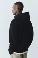 Campera con capucha en felpa de peso medio con interior cepillado suave. Modelo de hombros caídos con capucha y cordón para ajustar, cierre frontal y bolsillos delanteros. Puños y bajo en punto acanalado.