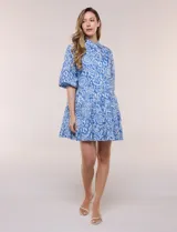 Vestido corto camisero de Elan, con diseño estampado en tonos de azul, cuello camisero clásico, mangas 3/4 abullonadas con elástico en los puños y falda con volantes fruncidos.