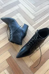 Botín de cuero vacuno color bronce metalizado, con diseño acordonado, cierre lateral interno y taco cuadrado.