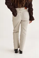 Pantalón engomado de tiro alto y pierna recta, color marrón, con acabado sutilmente brillante y bolsillos clásicos.