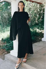 Vestido largo negro de la colección ZW de Zara, confeccionado en tejido satinado. Cuenta con un diseño asimétrico que incorpora una capa superpuesta y un corte fluido.