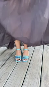 Sandalia de tacón cuadrado medio, con diseño de tiras horizontales y punta cuadrada. Presenta un acabado metalizado en color turquesa y cierre con pulsera al tobillo.