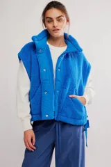 Chaleco de fleece color azul, de silueta oversized, con cierre frontal mediante botones a presión y bolsillos delanteros.