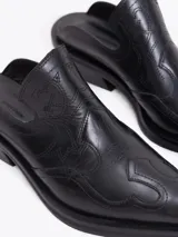 Zueco estilo western de cuero vacuno plateado, con costuras decorativas en la capellada, punta cuadrada y taco bajo de 4 cm.