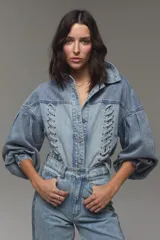 Campera de denim de algodón celeste, de corte boxy, con mangas abullonadas y detalles de trenzado con ojales metálicos en el frente.
