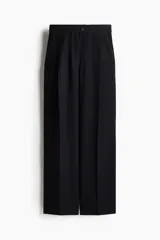 Pantalón sastrero de sarga color negro, de corte holgado y tiro alto. Presenta pinzas frontales, pretina con botón, bolsillos laterales al bies y piernas anchas con pliegues marcados.