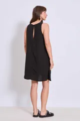 Vestido negro de corte holgado y largo a la rodilla, con cuello redondo y sin mangas. Presenta bordados florales en el escote y bolsillos laterales.