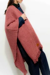 Ruana color rosa viejo de tejido de punto grueso con flecos en el borde inferior.