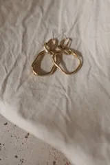 Aros colgantes de diseño artesanal con eslabones irregulares de textura orgánica y acabado en tono dorado.