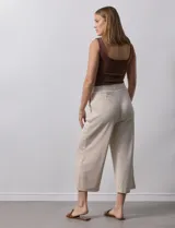 Pantalón capri plisado color beige, marca Dictionary, con pretina ancha elastizada y bolsillos delanteros.