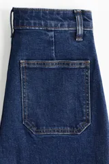 Jean wide leg de tiro alto en denim azul oscuro, con bolsillos delanteros tipo parche y pespuntes en contraste.