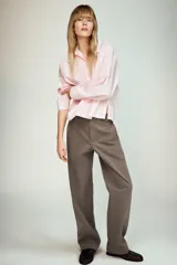 Camisa de popelín color rosa pálido, con cuello solapa, escote pico y manga larga terminada en puño. Cierre frontal con botones.