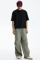 Remera negra de corte oversized y silueta holgada, confeccionada en punto liviano de algodón, con cuello redondo ribeteado y mangas cortas de hombros caídos.