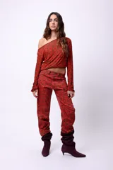 Pantalón de corte recto con estampado gráfico de letras en tonos rojo y marrón. Presenta cierre frontal con botón y bolsillos laterales.